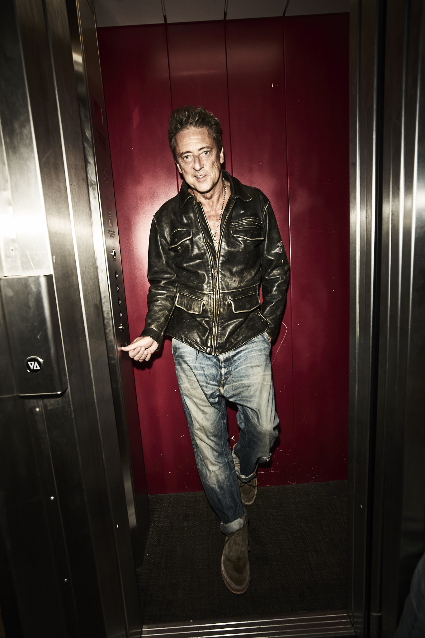 Jeremy Healy mid-stride in a red-lit lift, leather jacket